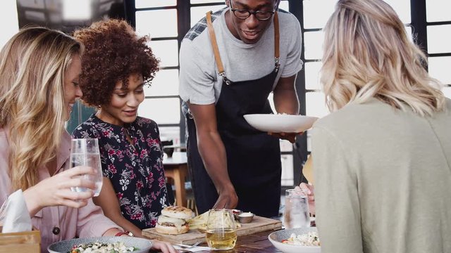 Four Young Female Friends Meeting For Drinks And Food Making A Toast In Restaurant