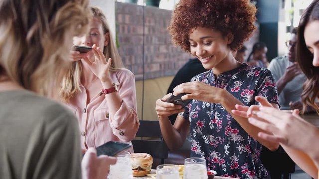 Four Female Friends Taking Photos Of Food In Restaurant To Post On Social Media