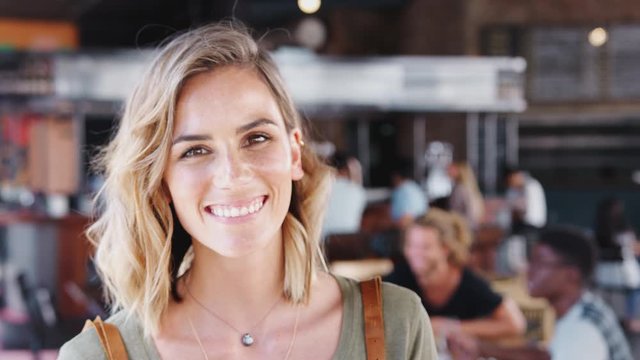 Portrait Of Waitress In Busy Bar Restaurant Smiling At Camera