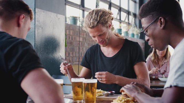Three Young Male Friends Meeting For Drinks And Food In Restaurant