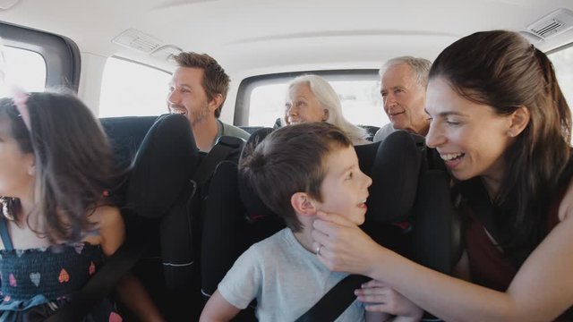 Multi Generation Family Sitting In Back Of People Carrier Being Driven To Vacation