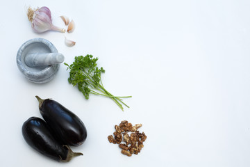 Mortar and pestle, garlic. vegetables and nuts on a white background. Healthy eating concept.