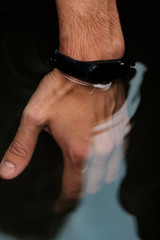 Waterproof fitness bracelet on a male hand. Check smart bracelet for water resistance. Male hand in the water. Modern technologies. Smart lifestyle concept.