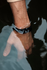 Fototapeta na wymiar Waterproof fitness bracelet on a male hand. Check smart bracelet for water resistance. Male hand in the water. Modern technologies. Smart lifestyle concept.