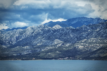 Breathtaking view of the village in the Boko Kotor Bay of the Rocky Mountains with thunderstorm clouds and the Adriatic Sea of Montenegro, soft focus