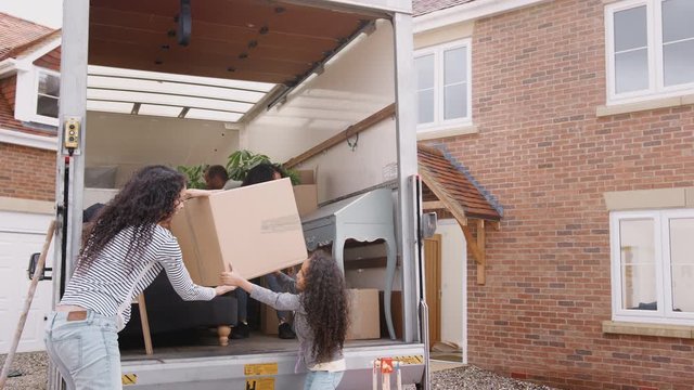 Family Unloading Furniture From Removal Truck Into New Home