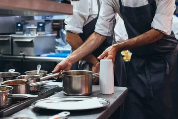 Foto op Plexiglas Onherkenbare chef-kok die voedsel kookt in de keuken van een restaurant © karrastock