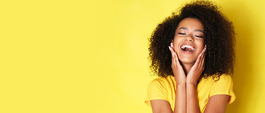 Super happy afro-american girl isolated on yellow background.
