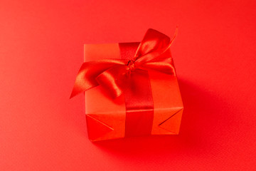 Christmas composition. Red gift box with a red ribbon on a red background. View from above. A Christmas gift
