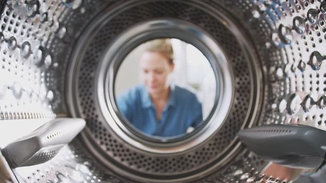 View Looking Out From Inside Washing Machine As Woman Puts In Laundry Load