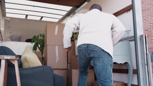 Man Unloading Boxes From Removal Truck Outside New Home On Moving Day