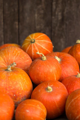 A lot of red ripe pumpkins on a old wooden background close up, holiday halloween. Pile of ripe pumpkins. Harvest autumn wallpaper