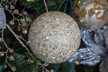 A silver bauble on a Christmas tree, with a shallow depth of field