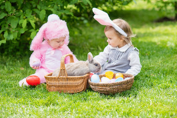 Children play with real rabbit. Laughing child at Easter egg hunt with pet bunny.