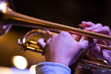 A trumpet player playing on a gold plated matte lacquered trumpet during a performance with other...