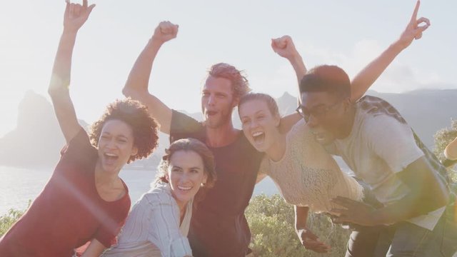 Men Lifting Up Women As Group Of Friends Have Fun Against Flaring Sun