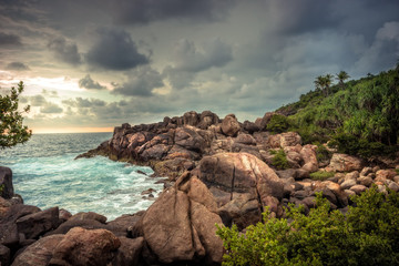 Rocky beach sea lagoon tropical scenery with palm trees and round stones with dramatic sunset sky vibrant colors in Sri Lanka