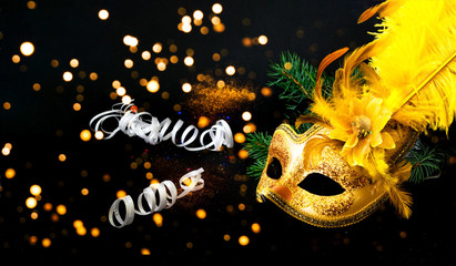 Masquerade mask on black background with confetti. New Years decor. Blurred effect. Close-up