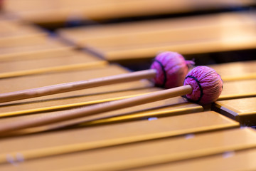 Percussion mallets with pink fibers resting on metal plates of a vibraphone