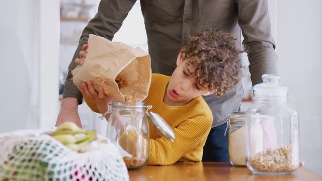 Father Helping Son To Refill Food Containers At Home Using Zero Waste Packaging