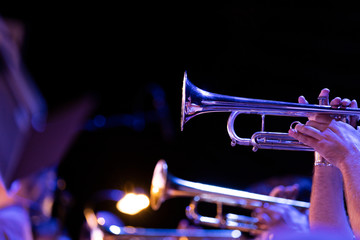 Fototapeta na wymiar Trumpet players of a big band section playing their horns in blue stage lighting