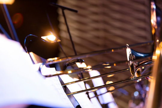 Trombone section of a big band on stage with music stand with lights in front of them