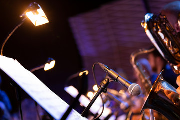 A microphone pointing into the bell of a saxophone in a big band setup