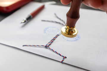 Notary public wax stamper. White envelope with brown wax seal, golden stamp. Responsive design mockup, flat lay. Still life with postal accessories.