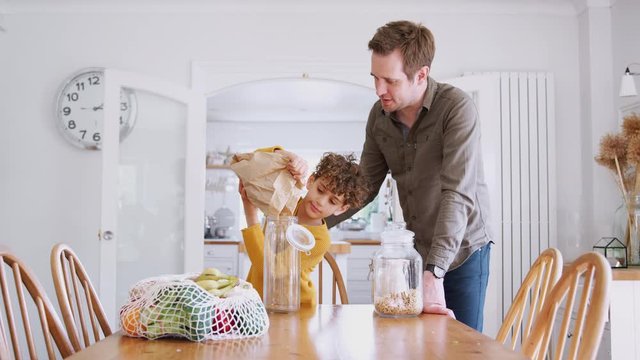 Father Helping Son To Refill Food Containers At Home Using Zero Waste Packaging