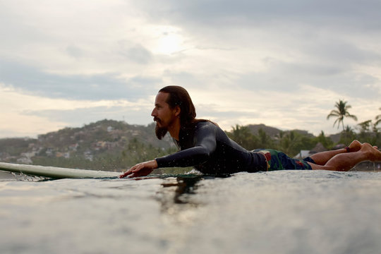 Male surfer paddling out on ocean