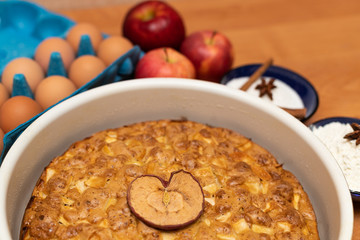 Apple pie with heart shaped Apple on wooden table with baking ingredients
