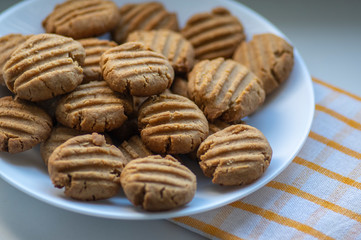 Pile of peanut butter biscuits on white plate, very tasty golden baked sweets, cookies served to eat