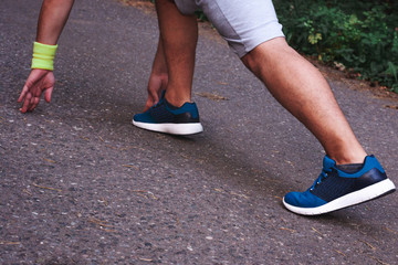 Feet step runner on the road, closeup shoes. Start running on the sidelines. Run outdoor exercise activity concept. Young handsome man jogging along a scenic path in a park