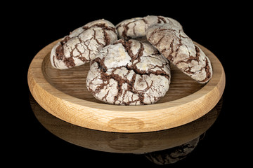 Group of four whole baked chocolate brownie cookie on bamboo plate isolated on black glass