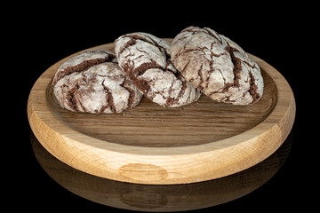 Group of three whole baked chocolate brownie cookie on bamboo plate isolated on black glass