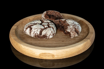 Group of one whole two halves of baked chocolate brownie cookie on bamboo plate isolated on black glass