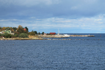 Fototapeta na wymiar Autumn sea landscape. View of the pier and the village. Cloudy weather, blue sea.