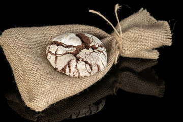 One whole baked chocolate brownie cookie on jute bag isolated on black glass