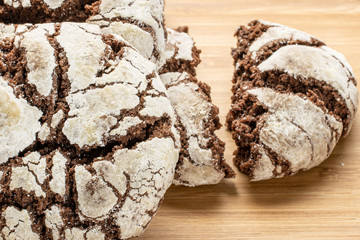 Group of two whole two halves of baked chocolate brownie cookie on natural wood