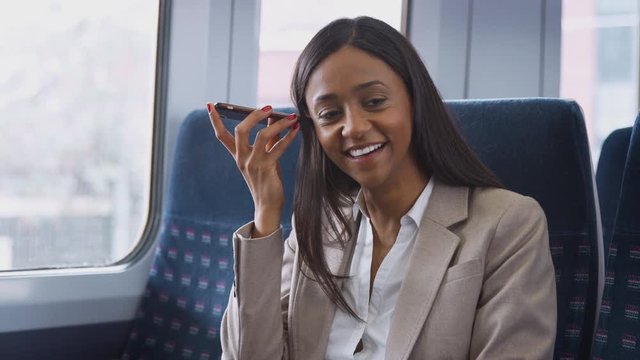 Businesswoman Sitting In Train Commuting To Work Using Mobile Phone