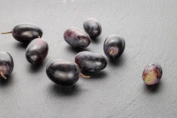 Lot of whole fresh black grape on grey stone