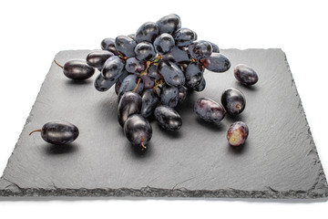 Lot of whole fresh black grape on grey stone isolated on white background