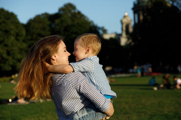 Fototapeta premium Mom and son have fun on the street. woman with a child smiling and laughing on the grass