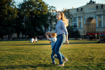 Mom and son have fun on the street. woman with a child smiling and laughing on the grass