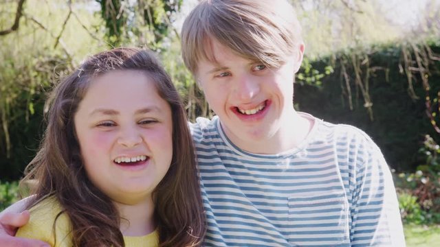Outdoor Portrait Of Loving Young Downs Syndrome Couple In Garden At Home Together