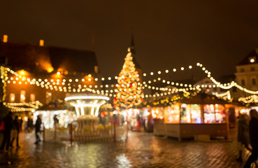 Obraz na płótnie Canvas winter holidays and celebration concept - blurred christmas market in winter evening at town hall square in tallinn, estonia