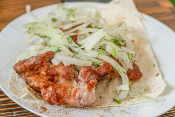 Meat skewers on pita bread with onions closeup