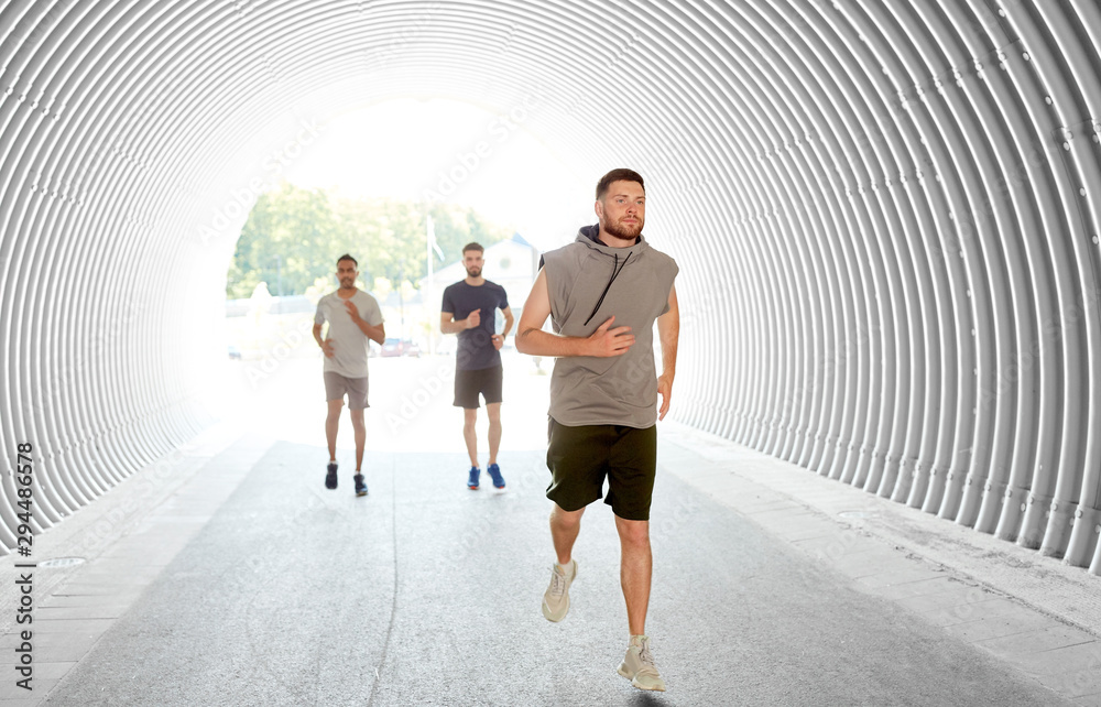 Sticker fitness, sport and healthy lifestyle concept - smiling young men or male friends running in tunnel