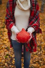 young white girl in a white sweater holds a pumpkin in her hands as a symbol of Halloween and Thanksgiving