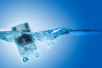 Money concept. Polish currency Zloty sinking in water as symbol of global financial crisis and uncertain future.